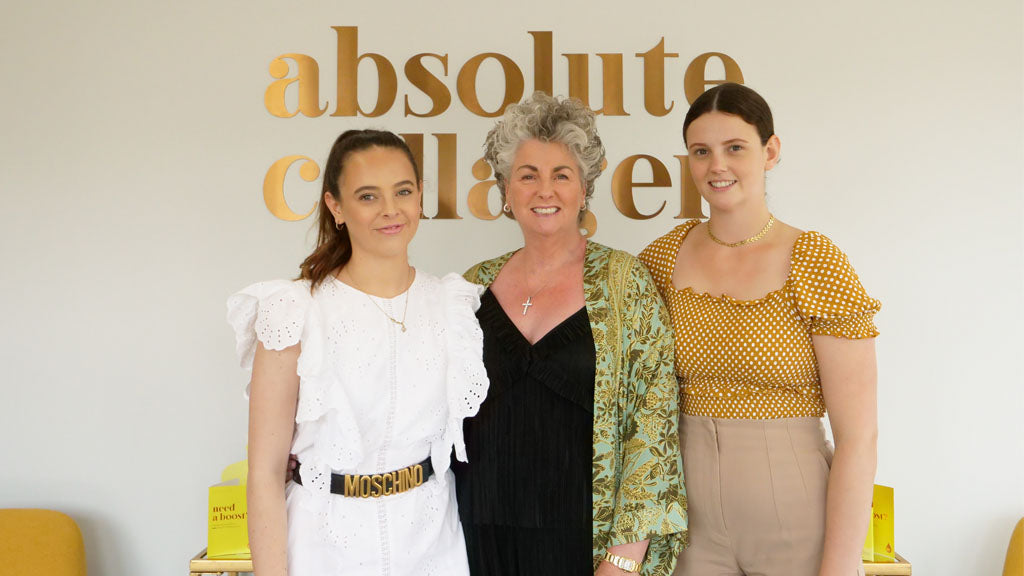 Photo showing a smiling Maxine, Margot and Darcy Laceby standing in front of a large copper Absolute Collagen sign